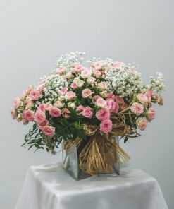 Imagen de recipiente de cristal con rosas de pitiminí en rosa y paniculata