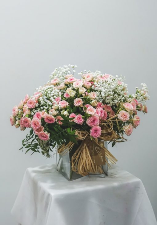 Imagen de recipiente de cristal con rosas de pitiminí en rosa y paniculata