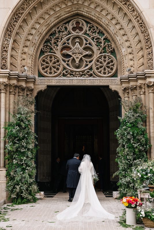 Entreda de la basílica San Vicente Ferrer de Valencia decorada con dos torres altas con flores y verdes en la puerta de entrada.